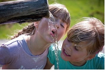 Flowing water from a pipe with two children drnking from it