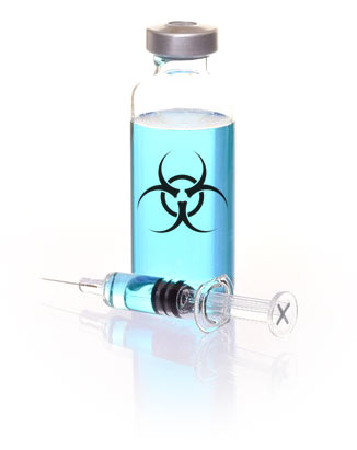 vaccine vial with light aqua colored liquid and a syringe lying beside the vial